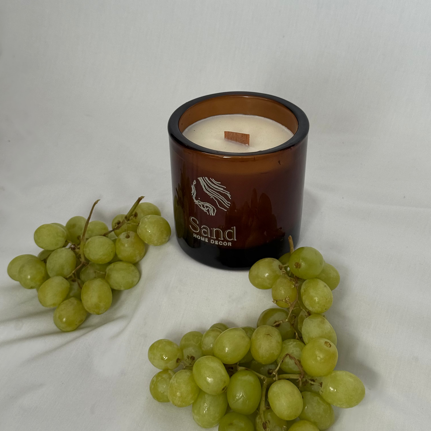 Candle with a wooden wick and grapes on a white background