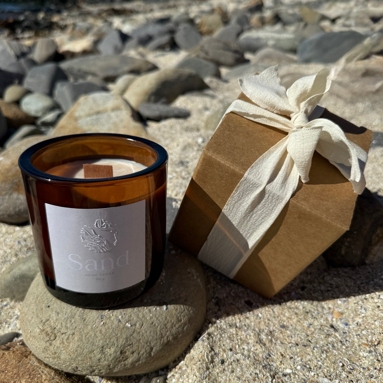 Large scented soy candle in an amber glass jar with a beach setting as the background.