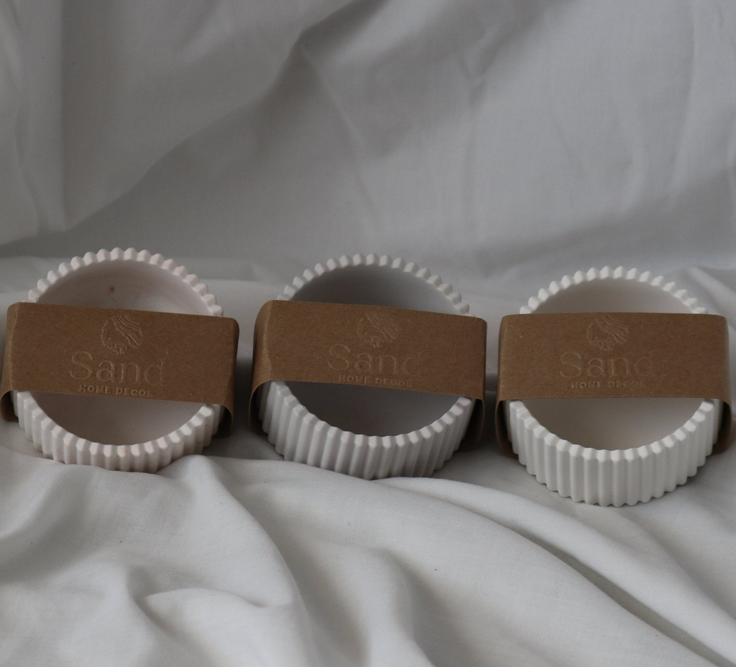 Three handmade ribbed trinket dishes wrapped in branded 'Sand Home Decor' brown kraft paper labels.