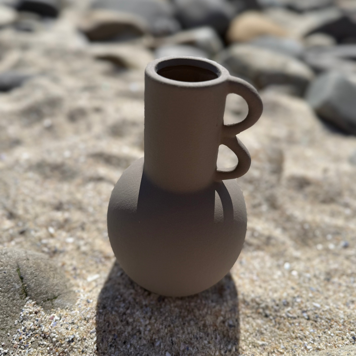 Matte mocha/ taupe-colored ceramic vase with a spherical base and two sculptural loop handles on a cylindrical neck.