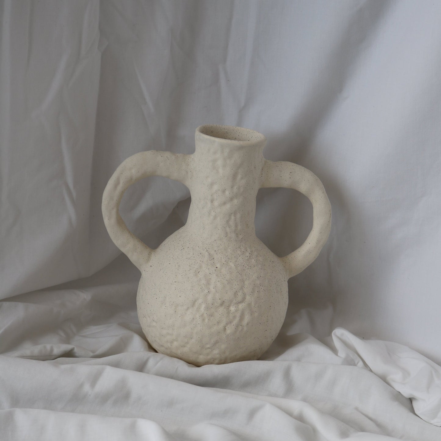 Tall textured large white vase with handles on each side.