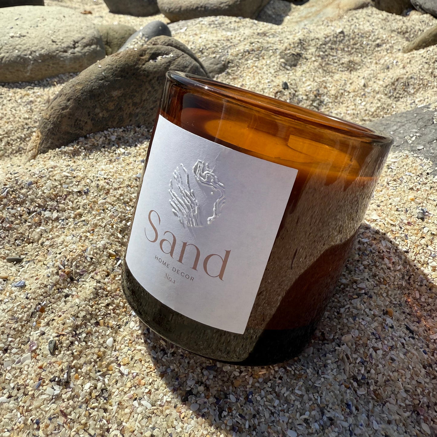 Large gin and tonic scented soy candle in an amber glass jar with a beach setting as the background.