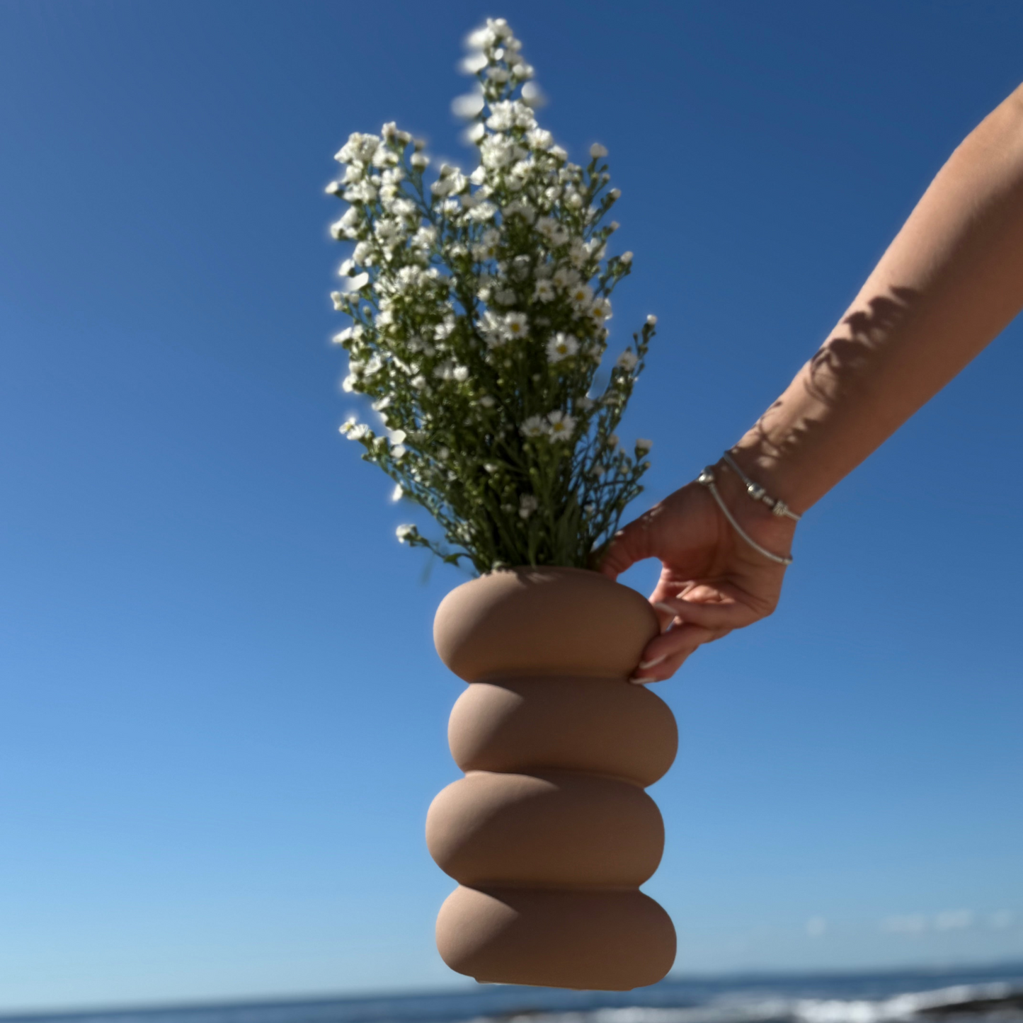 Contemporary ceramic vase with stacked pebble-inspired design in a smooth warm terracotta finish.