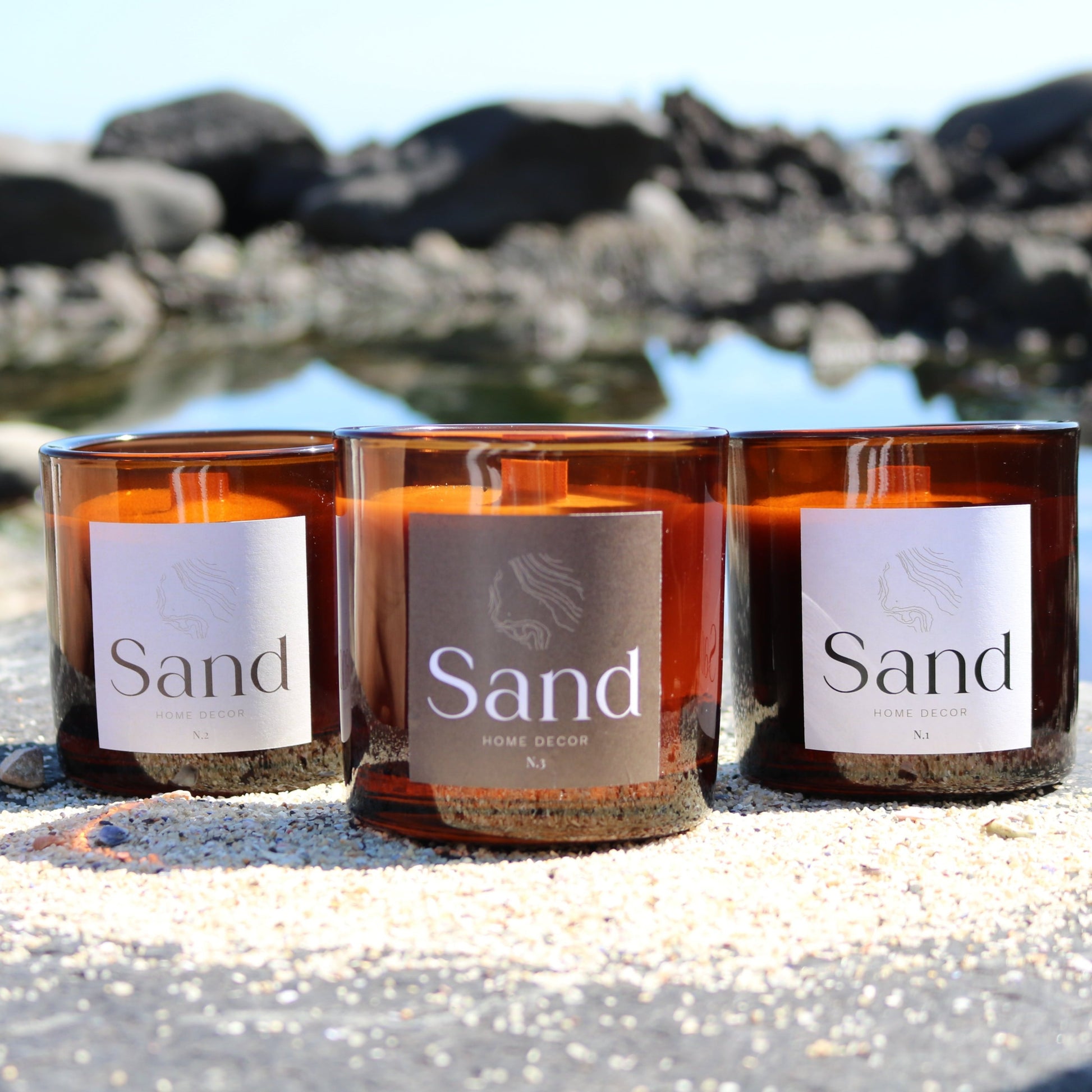 Large scented soy candle in an amber glass jar with a beach setting as the background. 