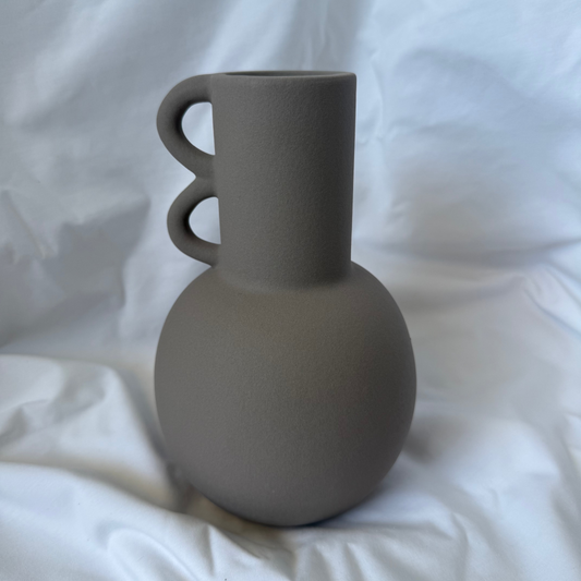 Matte mocha/taupe -colored ceramic vase with a spherical base and two sculptural loop handles on a cylindrical neck.