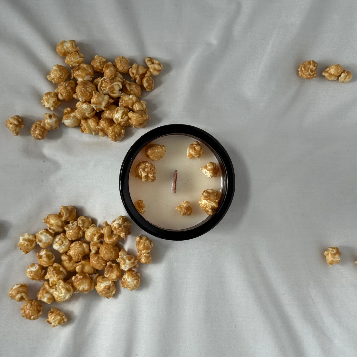 Candle with popcorn on a white fabric background