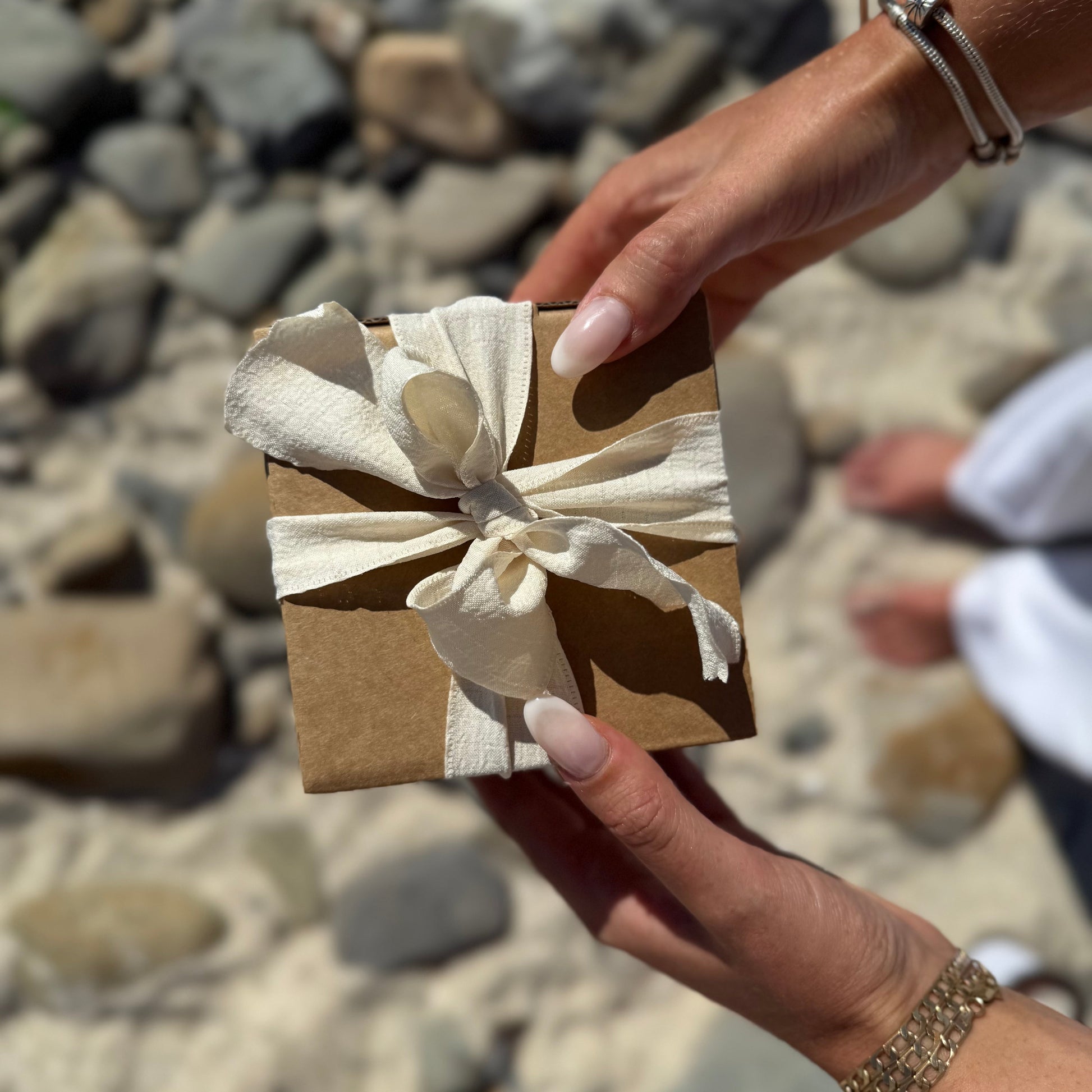 Large scented soy candle in its beautiful packaging wrapped in ribbon photographed on the beach. 