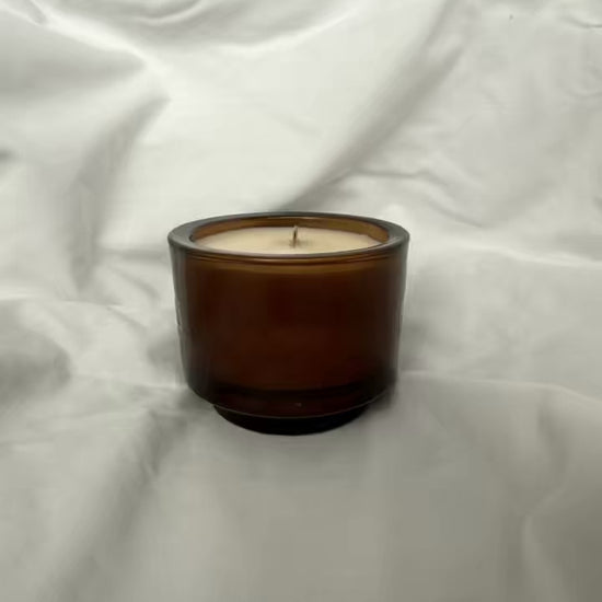 Video of handmade luxury candle turning to show logo and name. soy wax in a glass jar with a wooden wick 