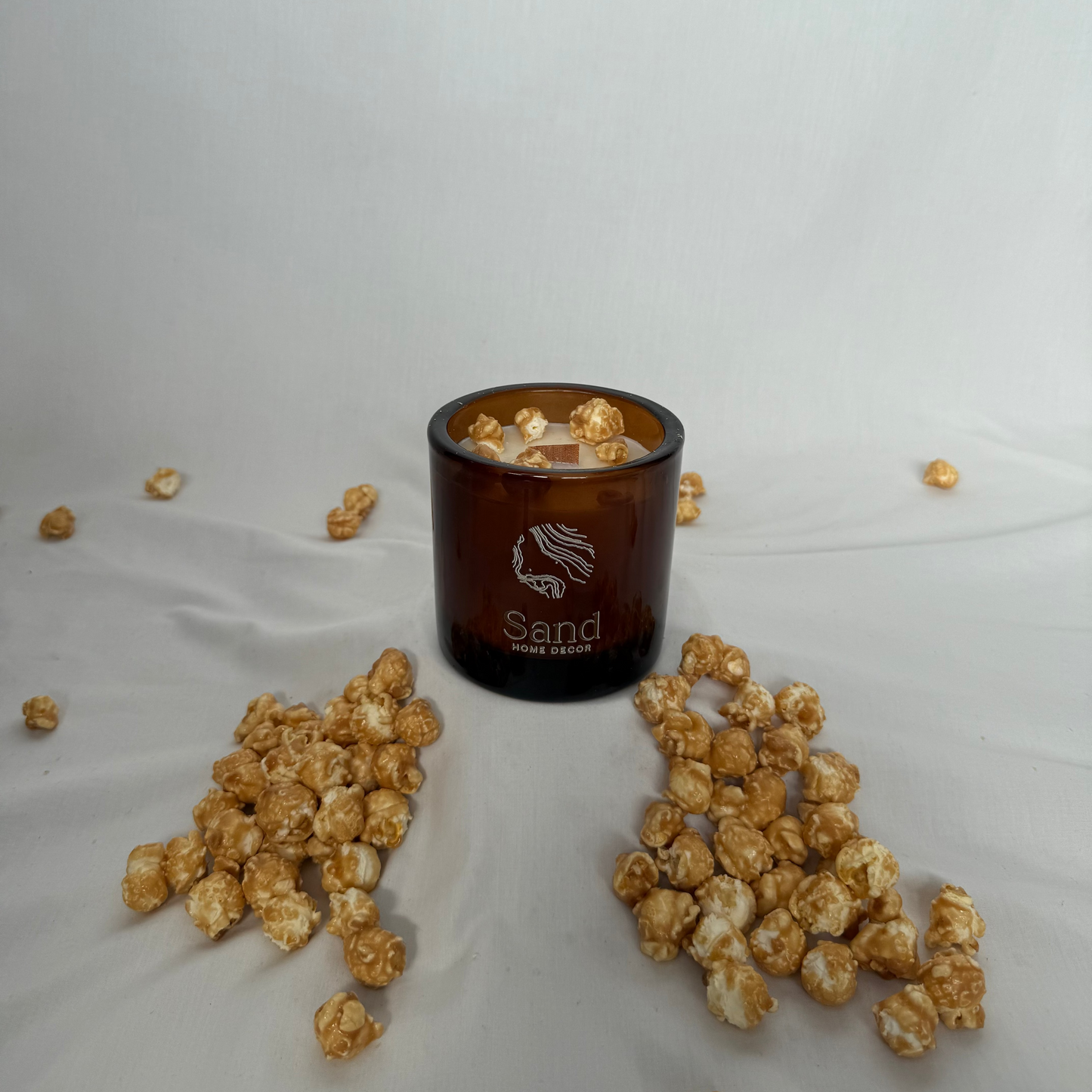 Candle with popcorn around it on a white background